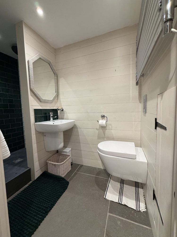 The bathroom: white panelled walls, basin and octagonal mirror